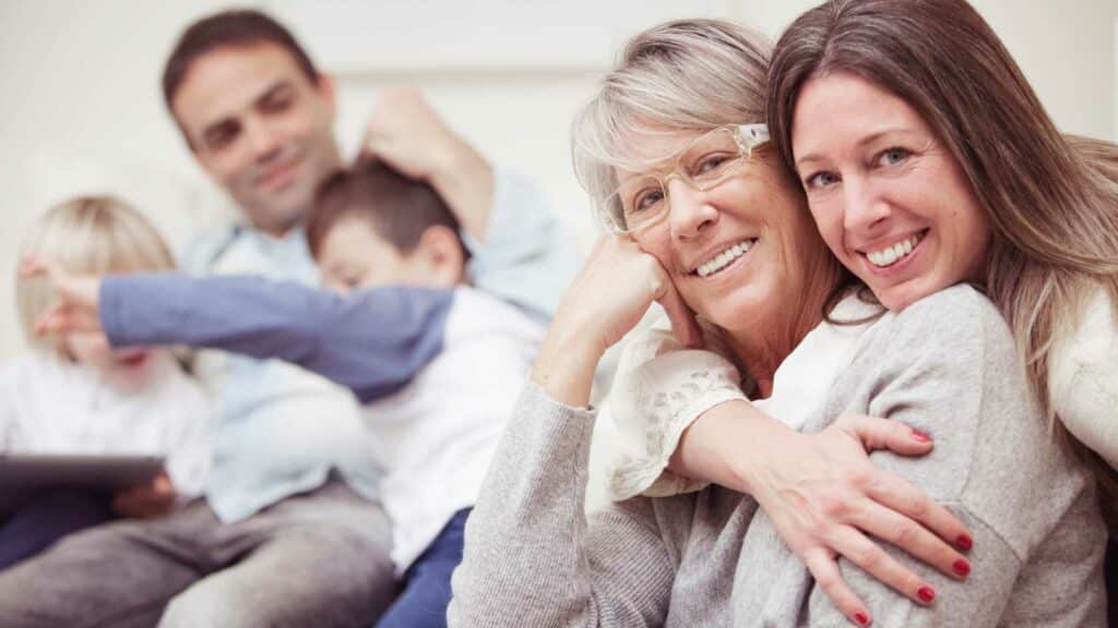 Young adult daughter hugging older mother with young dad hugging kids represents a young adult estate plan